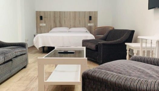 Amplia habitación en Hotel Madrid Río con sofá, cama doble y mobiliario moderno, ideal para descansar cerca del centro de Madrid.