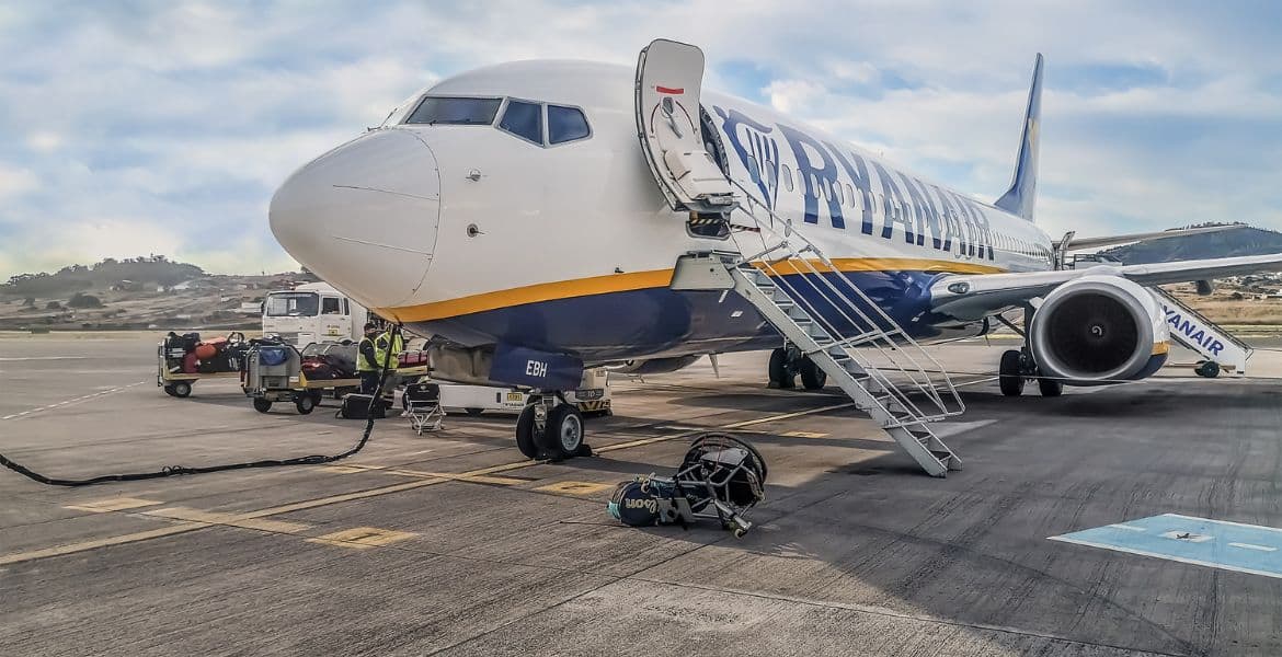 Avión de Ryanair en aeropuerto listo para vuelo, con equipaje y tripulación, en una imagen de temática de viajes y aerolíneas.