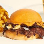 Una hamburguesa con papas fritas y cerveza en un restaurante de comida rápida.