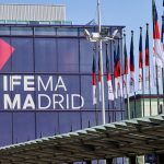 Fachada del centro de ferias IFEMA Madrid con banderas y logo destacado de IFEMA Madrid en un edificio moderno.