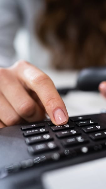 Servicio de teléfono hotel en Madrid Teclado de oficina con un dedo presionando una tecla, representación de servicios corporativos y atención al cliente en Hotel Madrid Río.