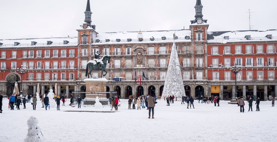 Edificio histórico con estación de metro en Madrid en invierno con nieve y turistas.