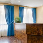 Amplia habitación de hotel con ventanas luminosas, cortinas azules y decoración clásica en Madrid Río. Perfecta para estancias cómodas cerca del centro de Madrid.