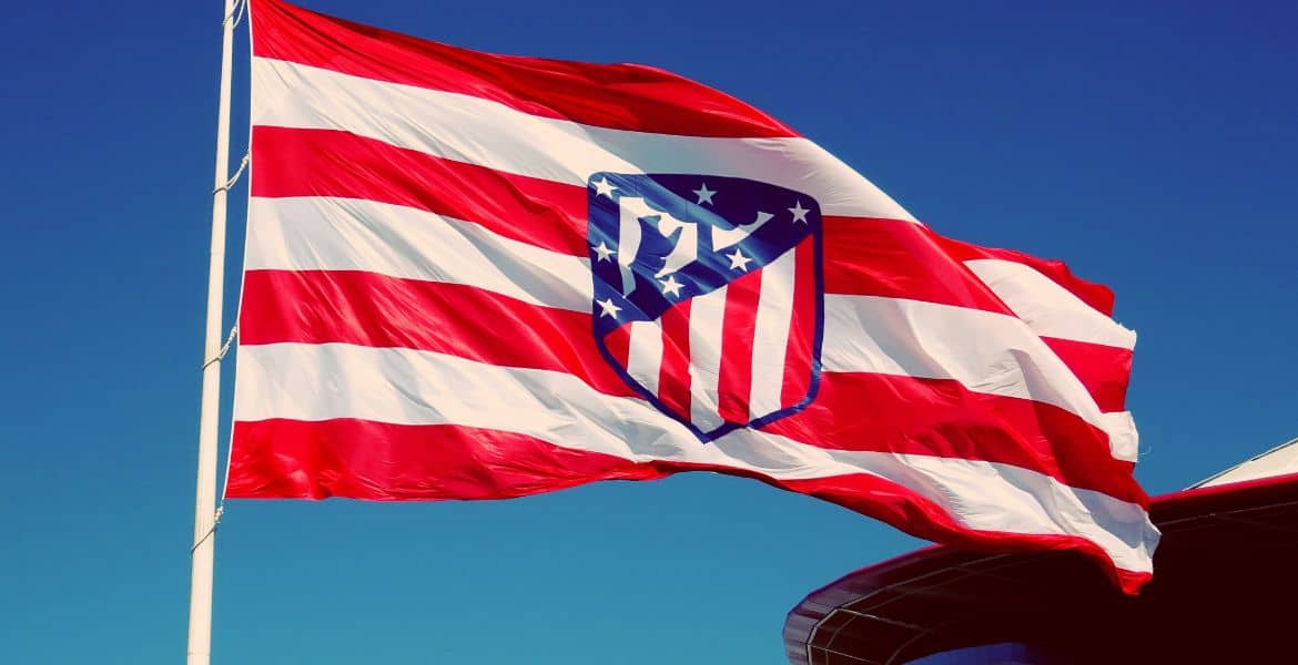 Bandera del Atlético de Madrid ondeando en el cielo azul con un hotel en Madrid Río, turismo deportivo, alojamiento en Madrid, hotel céntrico en Madrid, alojamiento cerca del estadio.