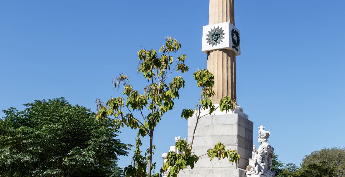 Lámpara en la Plaza de la Lealtad, cerca del Hotel Madrid Río, con árboles verdes y cielo azul, en Madrid, lugar turístico y cultural.