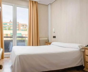 Conjunto de habitación moderna en Hotel Madrid Río con vistas al parque y a la ciudad, perfecta para estancias cómodas en Madrid.