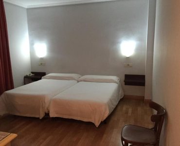 Habitación con camas dobles y mobiliario moderno en Hotel Madrid Río, perfecto para una estancia cómoda en Madrid.