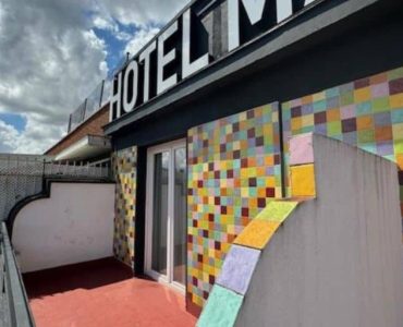 Colorido exterior del Hotel Madrid Río con azulejos decorativos y vistas al cielo nublado, ideal para estancias confortables en Madrid.