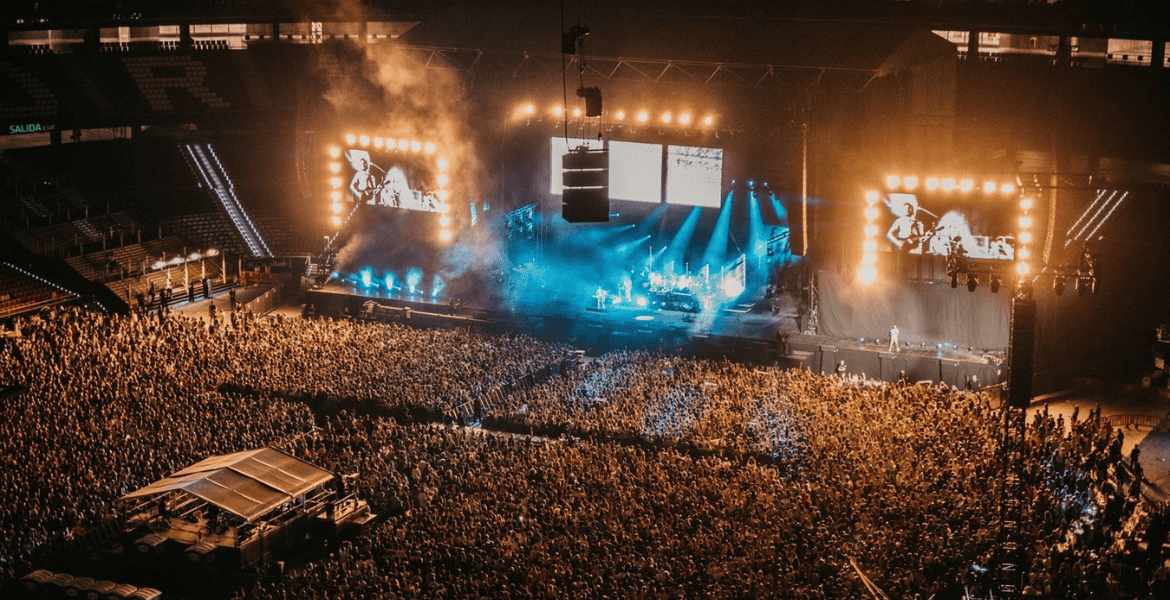 Amplia vista de un concierto en el estadio con escenario iluminado y gran aforo de público, en el entorno del Hotel Madrid Río.