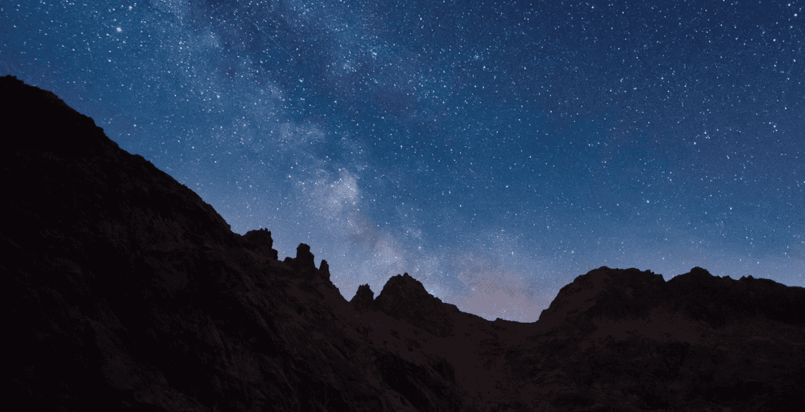 Cielo estrellado sobre montañas en Madrid, experiencia nocturna en la naturaleza cercana al Hotel Madrid Río.