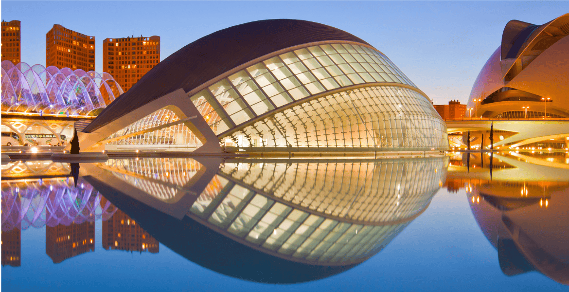 Moderno edificio cultural en Madrid Río reflejado en el agua, con iluminación nocturna, arquitectura vanguardista y entorno urbano en Madrid, ideal para hospedaje y turismo cultural.
