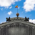 Techo del Hotel Madrid Río con detalles arquitectónicos y bandera española bajo cielo azul con nubes.