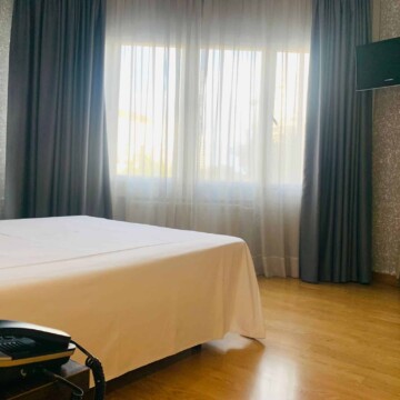 Luminoso habitación de hotel con cama doble, cortinas oscuras y televisión, cerca del río Madrid Río y atracciones turísticas, alojamiento cómodo en el centro de Madrid.
