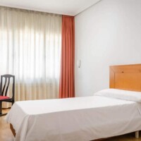 Habitación moderna en Hotel Madrid Río con cama sencilla y decoración luminosa.