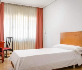 Habitación moderna en Hotel Madrid Río con cama sencilla y decoración luminosa.