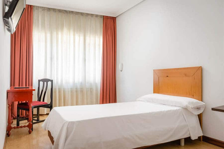 Habitación moderna en Hotel Madrid Río con cama sencilla y decoración luminosa.