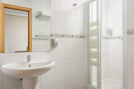 Limpieza y funcionalidad en habitaciones del Hotel Madrid Río, con baño moderno y espacio cómodo para una estancia cómoda en Madrid.