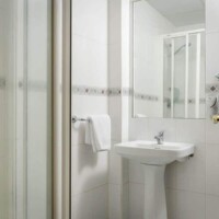 Amplio cuarto de baño moderno con ducha, lavabo y toalla, en hotel Madrid Río con servicios de calidad y ubicación privilegiada en Madrid.