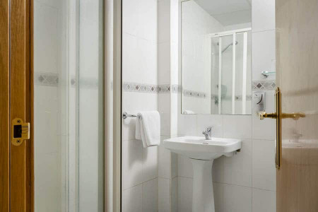 Amplio cuarto de baño moderno con ducha, lavabo y toalla, en hotel Madrid Río con servicios de calidad y ubicación privilegiada en Madrid.