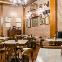 Cómoda decoración de estilo vintage en restaurante con paredes de ladrillo visto y mobiliario de madera. Ambiente acogedor en Hotel Madrid Río para cenas y desayunos.