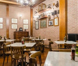 Cómoda decoración de estilo vintage en restaurante con paredes de ladrillo visto y mobiliario de madera. Ambiente acogedor en Hotel Madrid Río para cenas y desayunos.