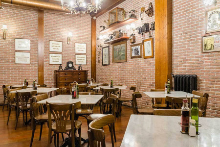 Cómoda decoración de estilo vintage en restaurante con paredes de ladrillo visto y mobiliario de madera. Ambiente acogedor en Hotel Madrid Río para cenas y desayunos.