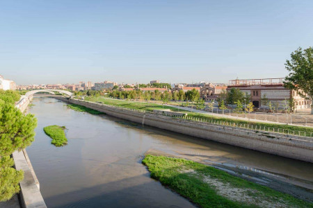 Vistas del río Manzanares y el Parque del Madrid Río con zonas verdes y arquitectura moderna en Madrid.