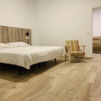 Amplia habitación de hotel en Madrid con cama doble, moderna decoración y zona de descanso con sofá, ubicada en Hotel Madrid Río, confort y alojamiento céntrico en Madrid.