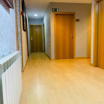 Puerta de habitación en hotel Madrid Río con suelo de madera y paredes decoradas, área interior moderna y acogedora, cerca del río y parques de Madrid.
