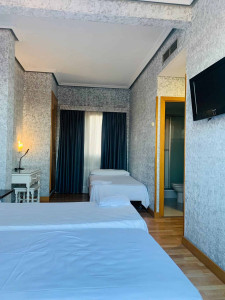 Habitación moderna en Hotel Madrid Río con camas cómodas, televisión y baño privado.