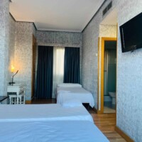 Habitación moderna en Hotel Madrid Río con camas cómodas, televisión y baño privado.