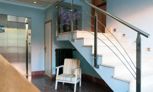 Amplia escalera de hotel en Madrid Río con diseño moderno y detalles decorativos, ideal para viajeros que buscan comodidad y estilo en su alojamiento.