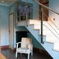 Amplia escalera de hotel en Madrid Río con diseño moderno y detalles decorativos, ideal para viajeros que buscan comodidad y estilo en su alojamiento.