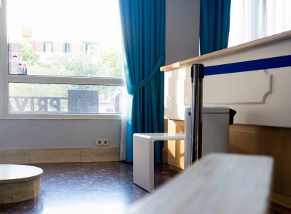 Puerta de habitación de hotel con ventana y cortinas azules, interior luminoso y cómodo en Hotel Madrid Río, ideal para viajeros que buscan alojamiento en Madrid.