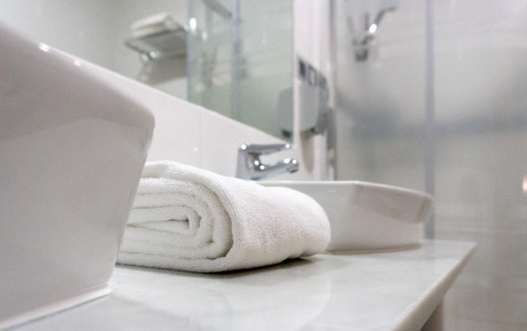 Lavabo con toallas blancas en baño moderno en Hotel Madrid Río, alojamiento céntrico en Madrid con instalaciones cómodas y elegantes.