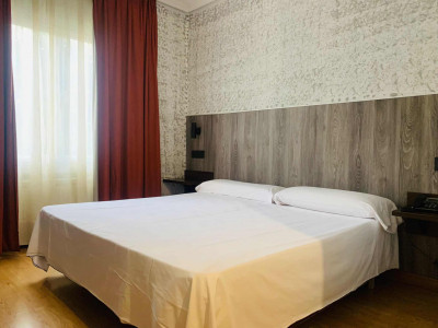 Habitación moderna y acogedora en Hotel Madrid Río con cama doble, decoración elegante y vistas a la ciudad, ideal para estancias confortables en Madrid.