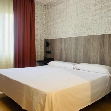 Habitación moderna y acogedora en Hotel Madrid Río con cama doble, decoración elegante y vistas a la ciudad, ideal para estancias confortables en Madrid.