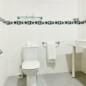 Clean and modern hotel bathroom with white tiles, glass shelf, towel rack, and sink, offering comfort and convenience in Madrid Río area.