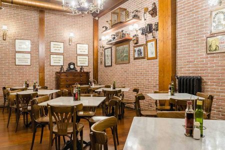 Cómodo restaurante con decoración vintage y paredes de ladrillo, ideal para restaurantes en Madrid Río. Ambiente acogedor con mesas para cenas en grupo.